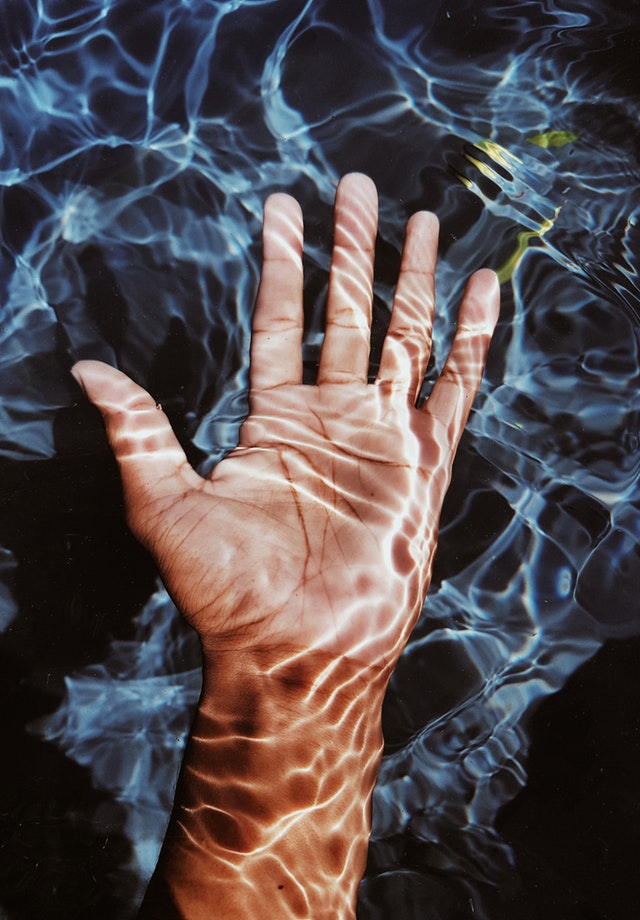 A hand is shown in the water.