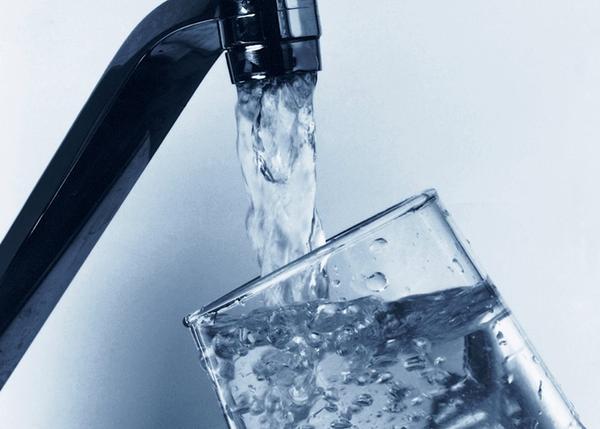 A faucet is pouring water into a glass.